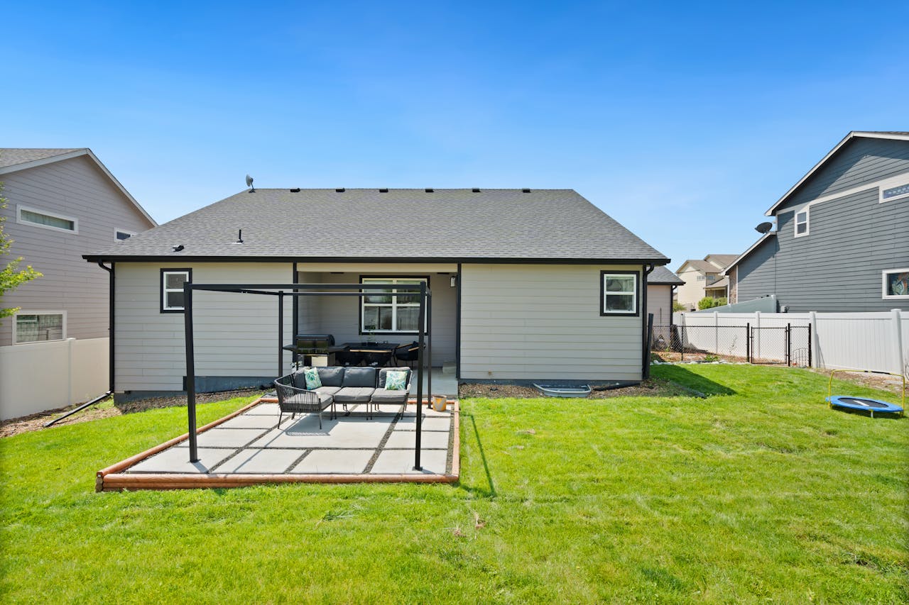 A pristine backyard with patio furniture, surrounded by residential homes and a lush lawn.