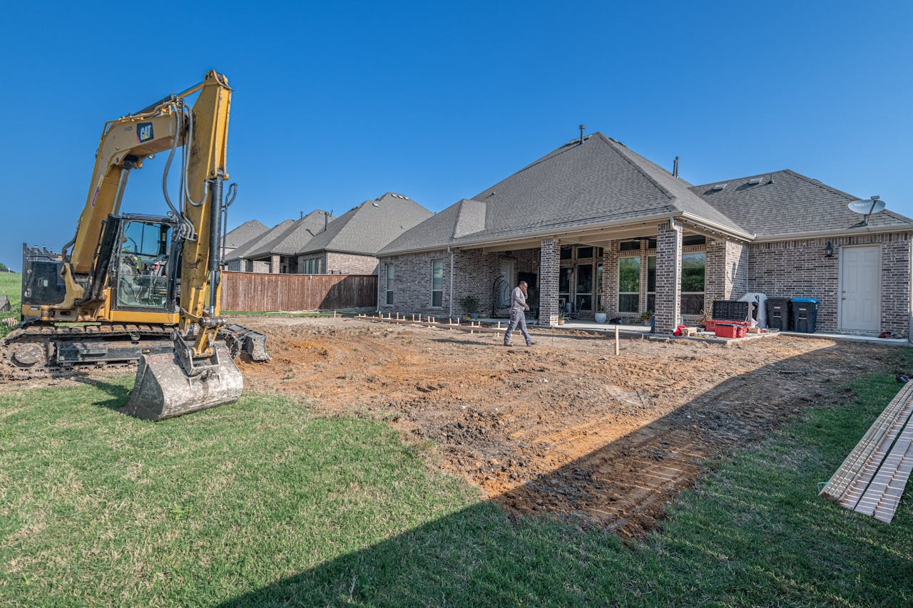 A construction site for a new patio in a Texas backyard with heavy machinery.